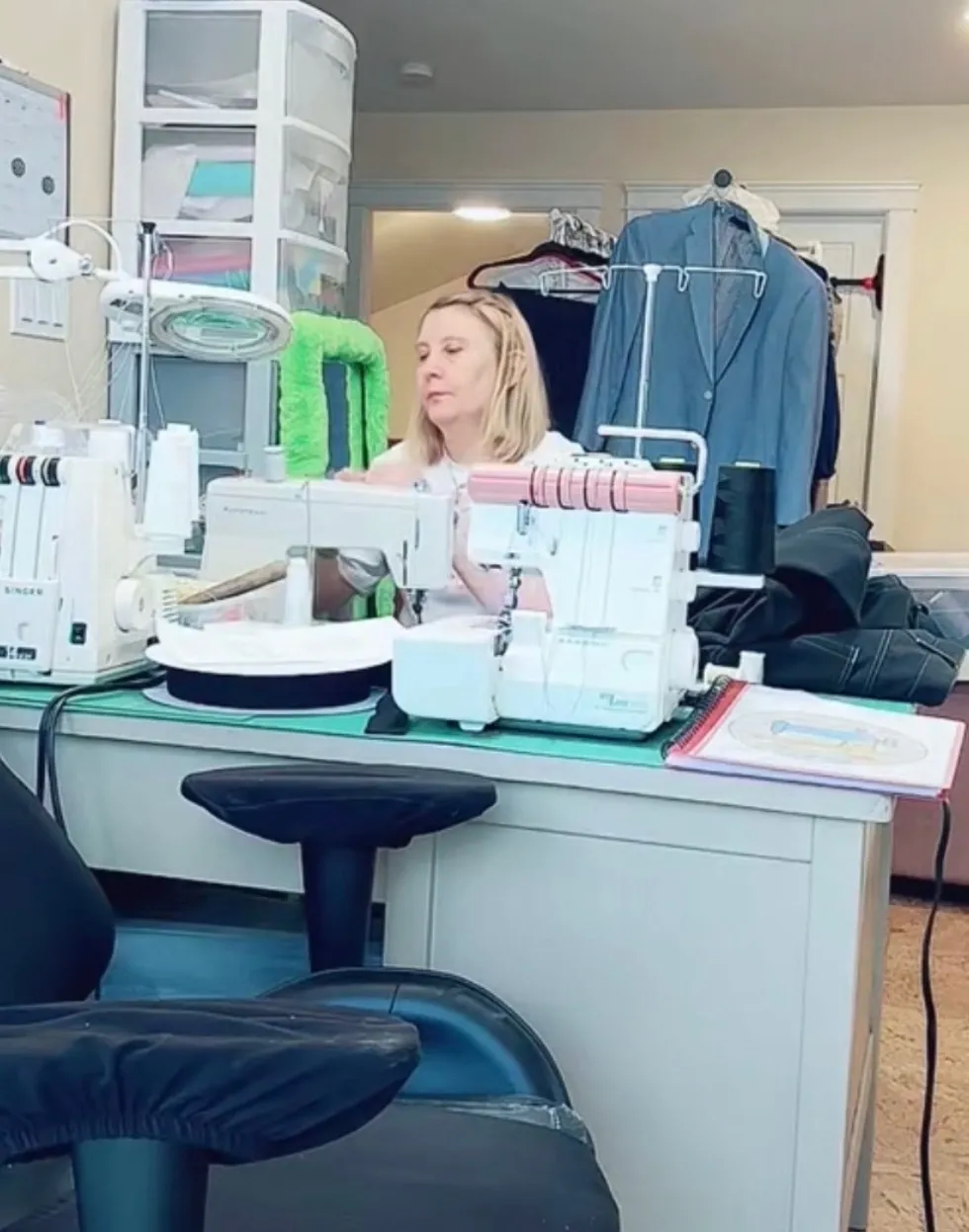 Alla's home sewing studio in Comox — sewing machines, serger and garments on the rail.